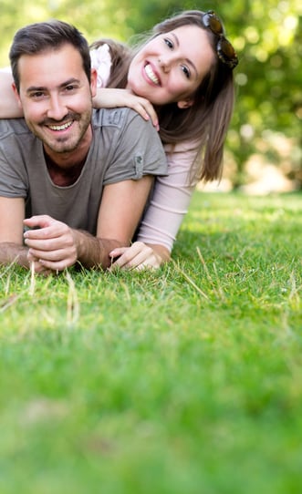 Playful couple smiling and lying at the park