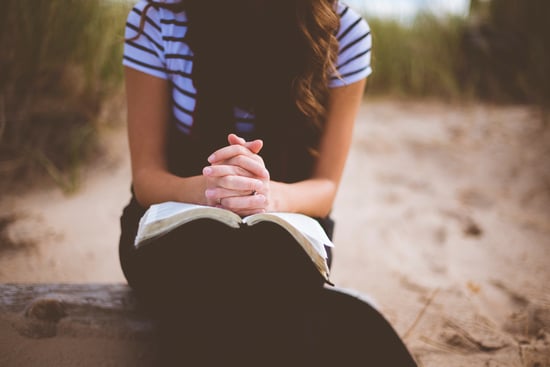 woman with clutched hands and book